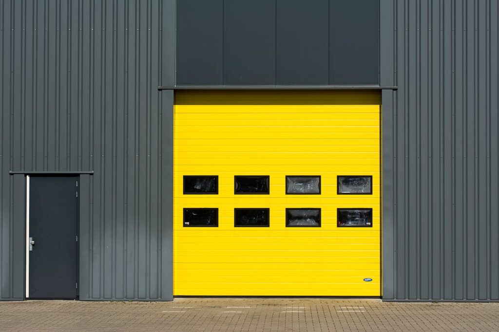 Custom commercial garage doors in Vancouver – repair, installation, and maintenance experts. A sleek industrial structure featuring a vibrant yellow garage door for architectural interest Delta